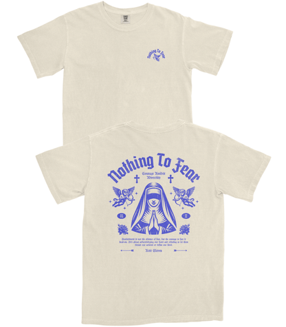 Two views of an off-white t-shirt showing the front and back. The front features a small blue graphic on the left chest, and the back features a large blue graphic with the text 'Nothing To Fear' and a stylized nun illustration.