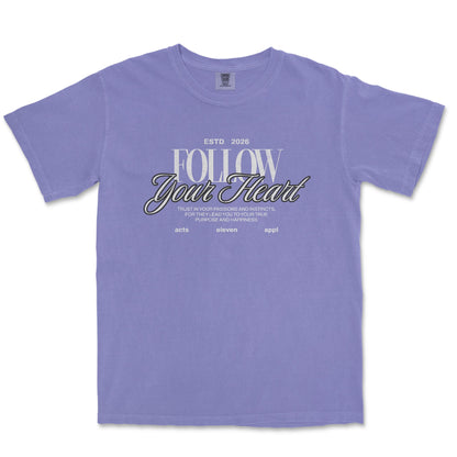 A lavender purple short-sleeve t-shirt with a graphic on the chest reading 'FOLLOW Your Heart' in white and black script, displayed flat against a white background.