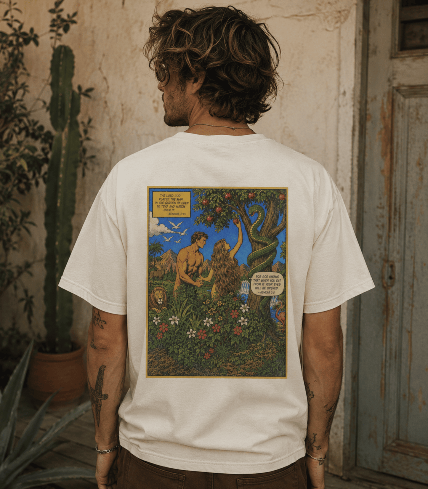 A man viewed from behind wearing a white t-shirt with a large, colorful graphic print on the back depicting a mythological scene of a man and a lion in a garden.