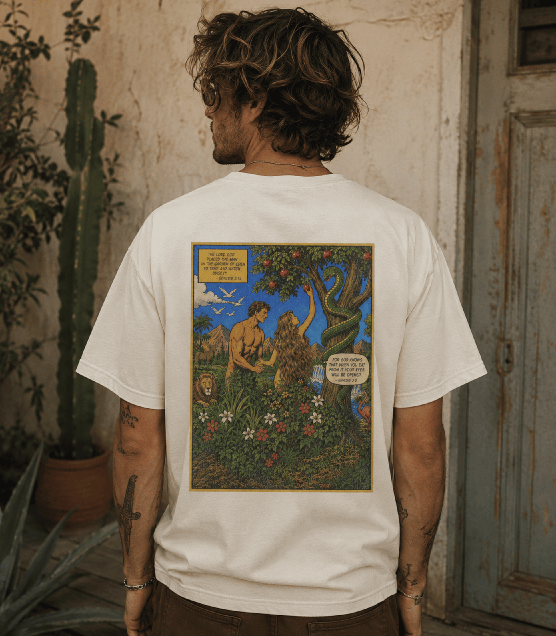 A man viewed from behind wearing a white t-shirt with a large, colorful graphic print on the back depicting a mythological scene of a man and a lion in a garden.
