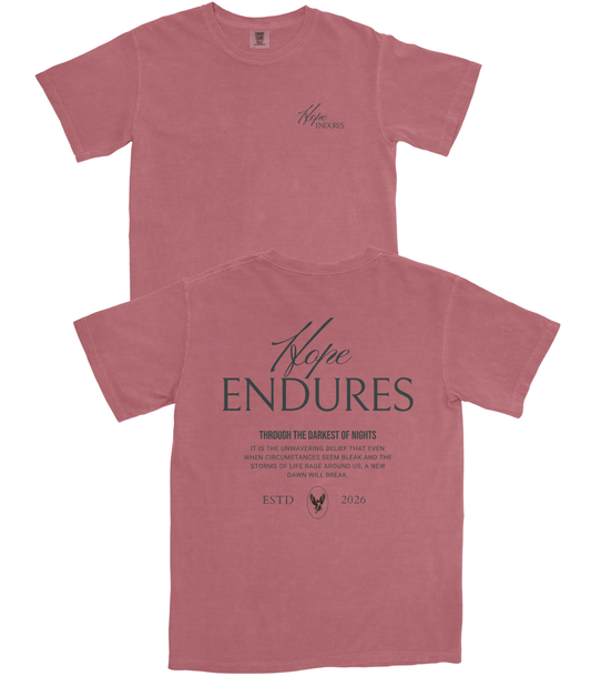 A dusty rose short-sleeve t-shirt shown from both the front and back. The front features a small, subtle script logo on the left chest, while the back displays a large, dark gray graphic reading 'Hope ENDURES' with a quote underneath and 'ESTD 2026' at the bottom.