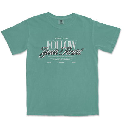 A teal green short-sleeve t-shirt with a graphic on the chest that reads 'FOLLOW Your Heart' in white and black script, displayed flat against a white background.