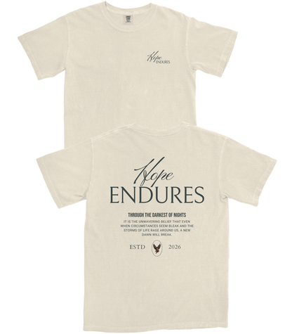 Two cream-colored t-shirts shown against a white background, displaying the front and back designs. The front features a small 'Hope ENDURES' logo on the left chest, while the back features a large, matching graphic with inspirational text and a small bird emblem.
