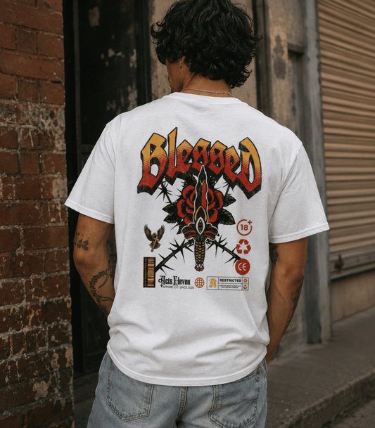 A man viewed from behind wearing a white t-shirt with a large graphic print on the back. The graphic features the word 'Blessed' in a red and yellow font above a black and red butterfly design with crossed thorns and a knife.