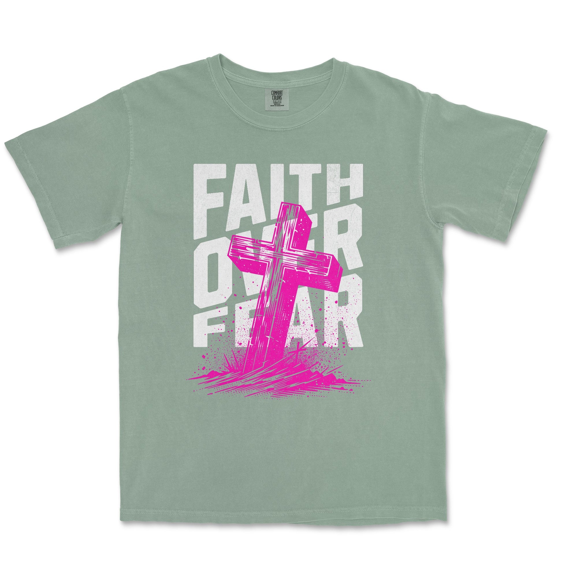 A sage green short-sleeve t-shirt with a graphic print on the front featuring the words 'FAITH OVER FEAR' in distressed white letters and a bright pink cross layered over them.
