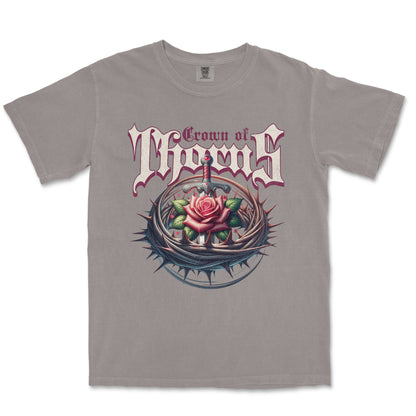 A gray short-sleeve crewneck t-shirt featuring a graphic print of the band Crown of Thorns. The design displays the band's name in a stylized gothic font above an illustration of a pink rose with thorns and a dagger.